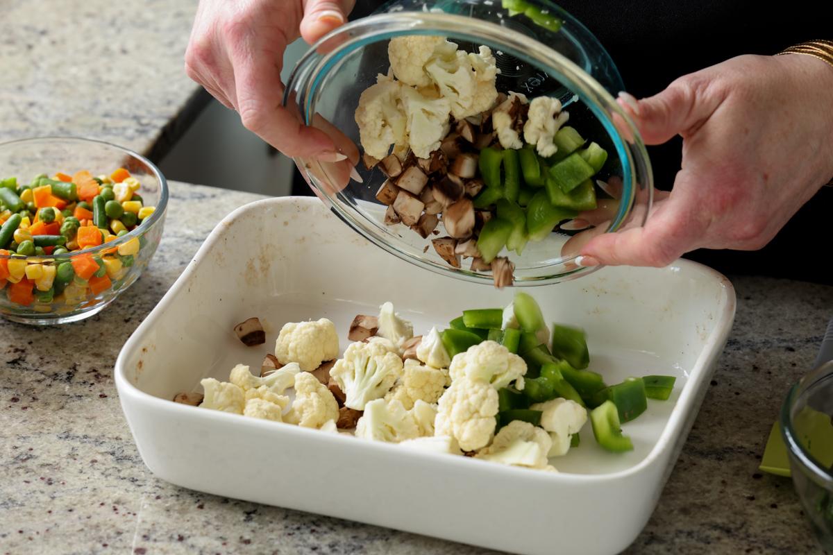 adding fresh veggies to the casserole dish