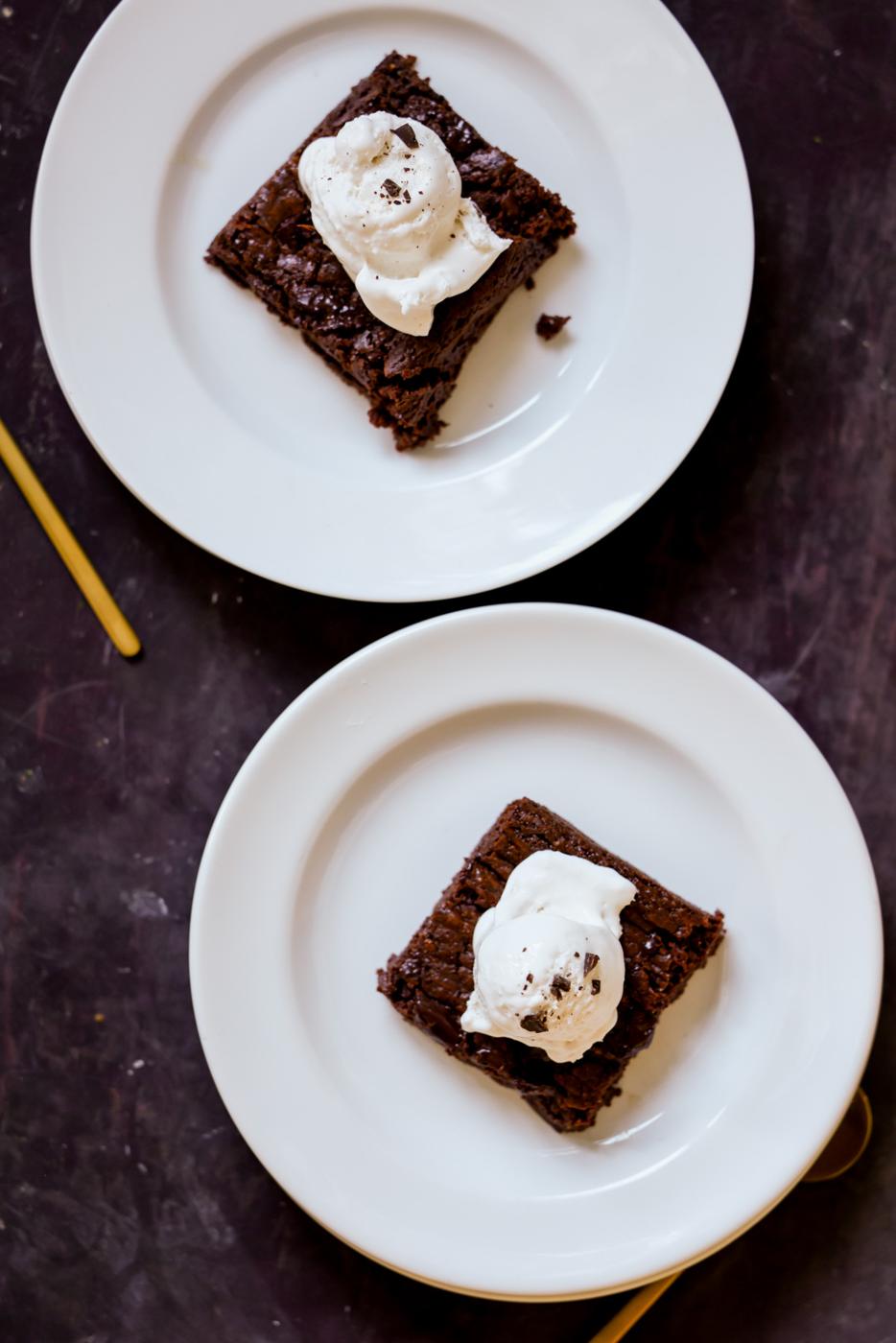 almond butter brownies on plates topped with vegan ice cream