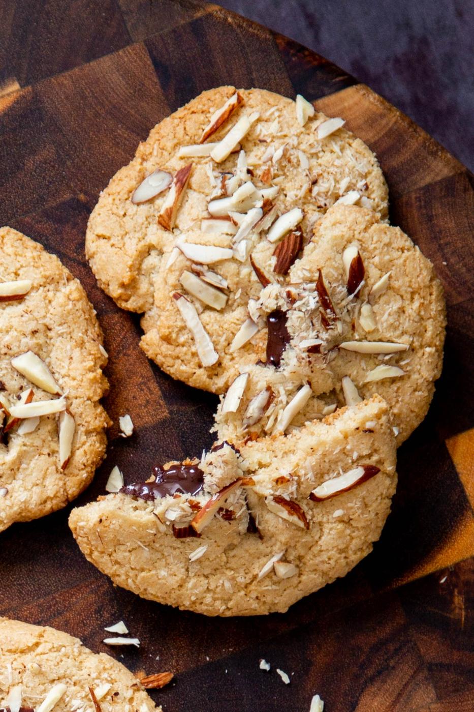 halved vegan almond joy cookies with half melted chocolate chunks peaking out on a wooden board