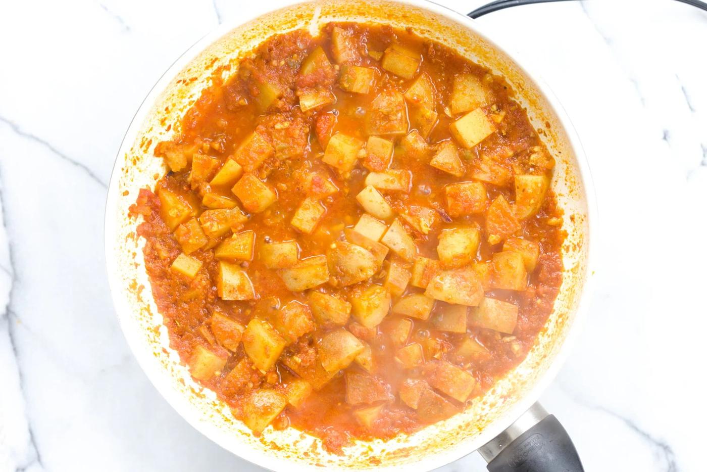 aloo matar simmering in a white skillet