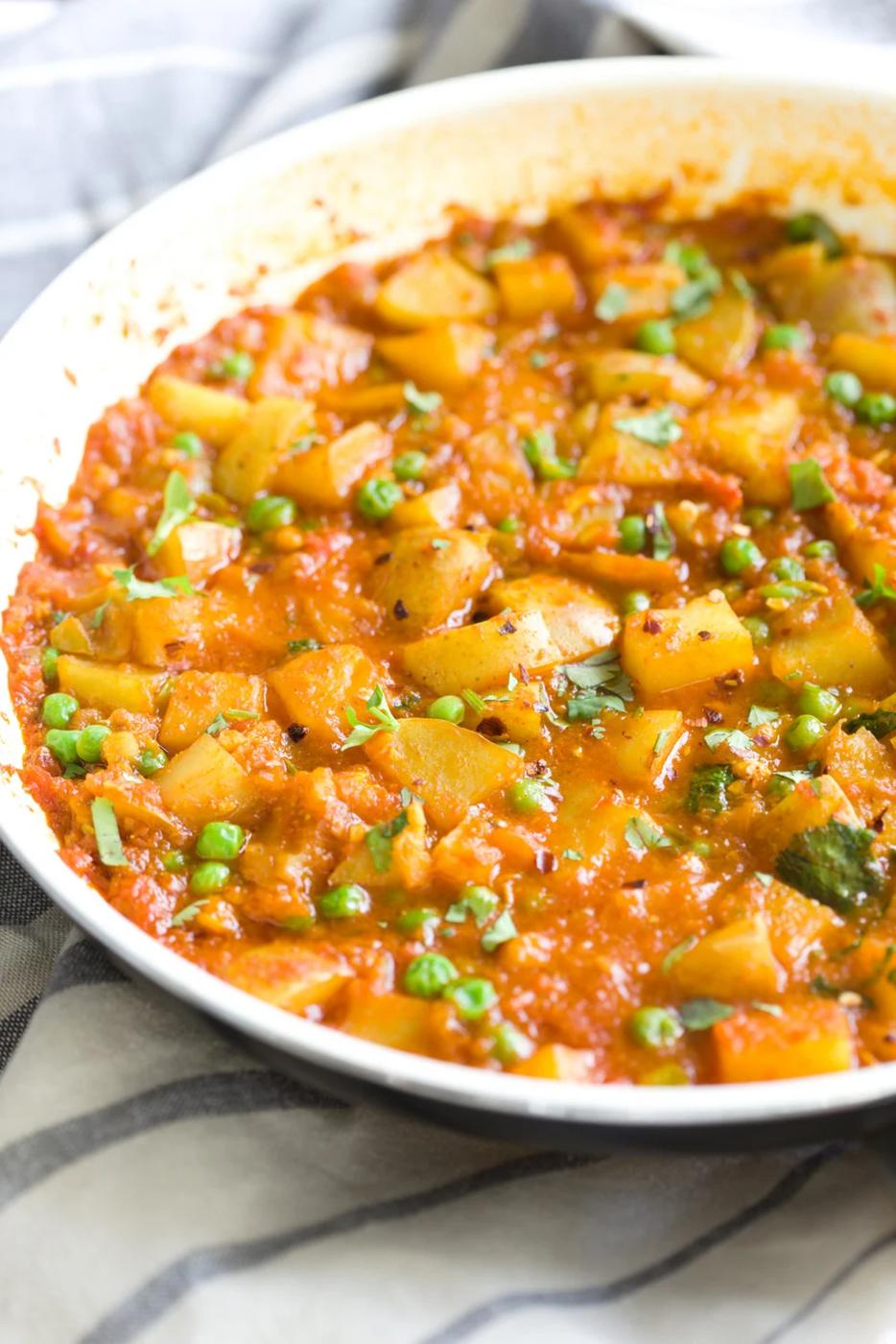 side view of a skillet with vegan aloo matar potato pea curry