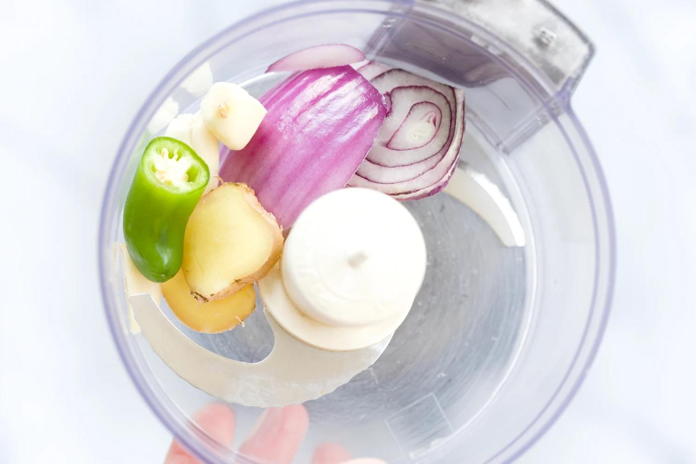 ginger, red onion, garlic and green chili being chopped in a small food processor
