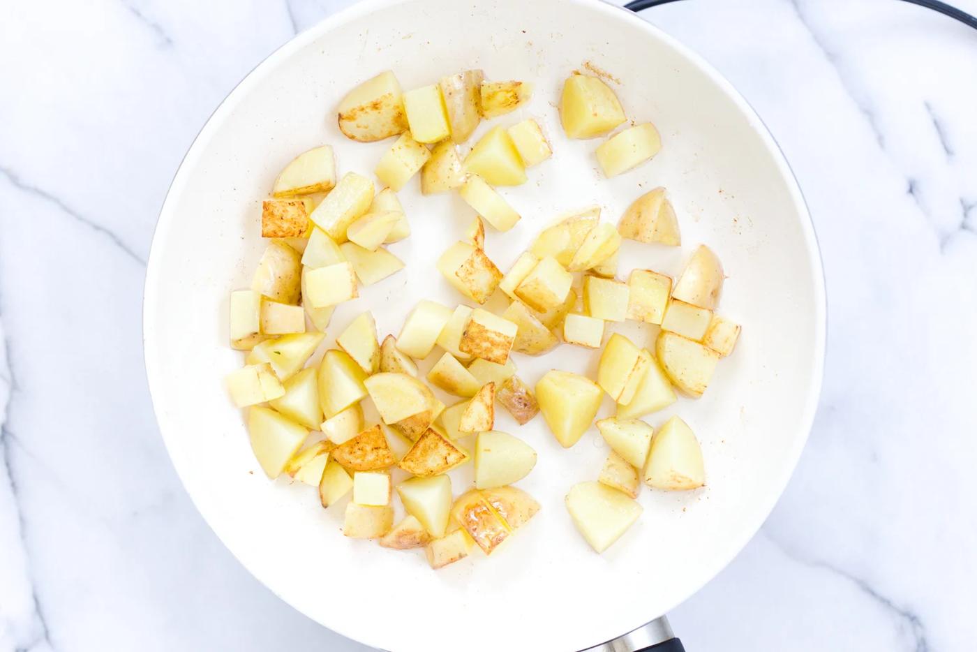 overhead shot of sauteed potato cubes in a white bowl