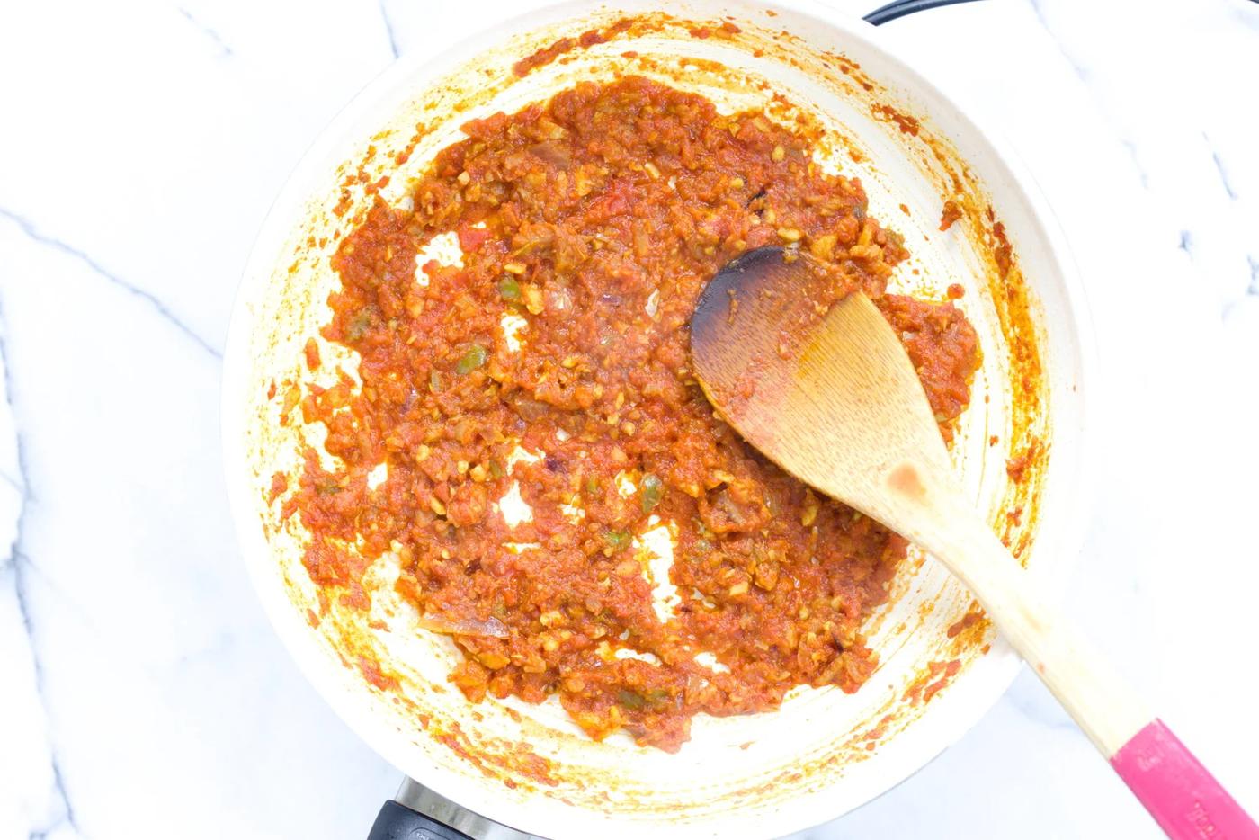 tomato base for aloo matar peas and potatoes in a white skillet
