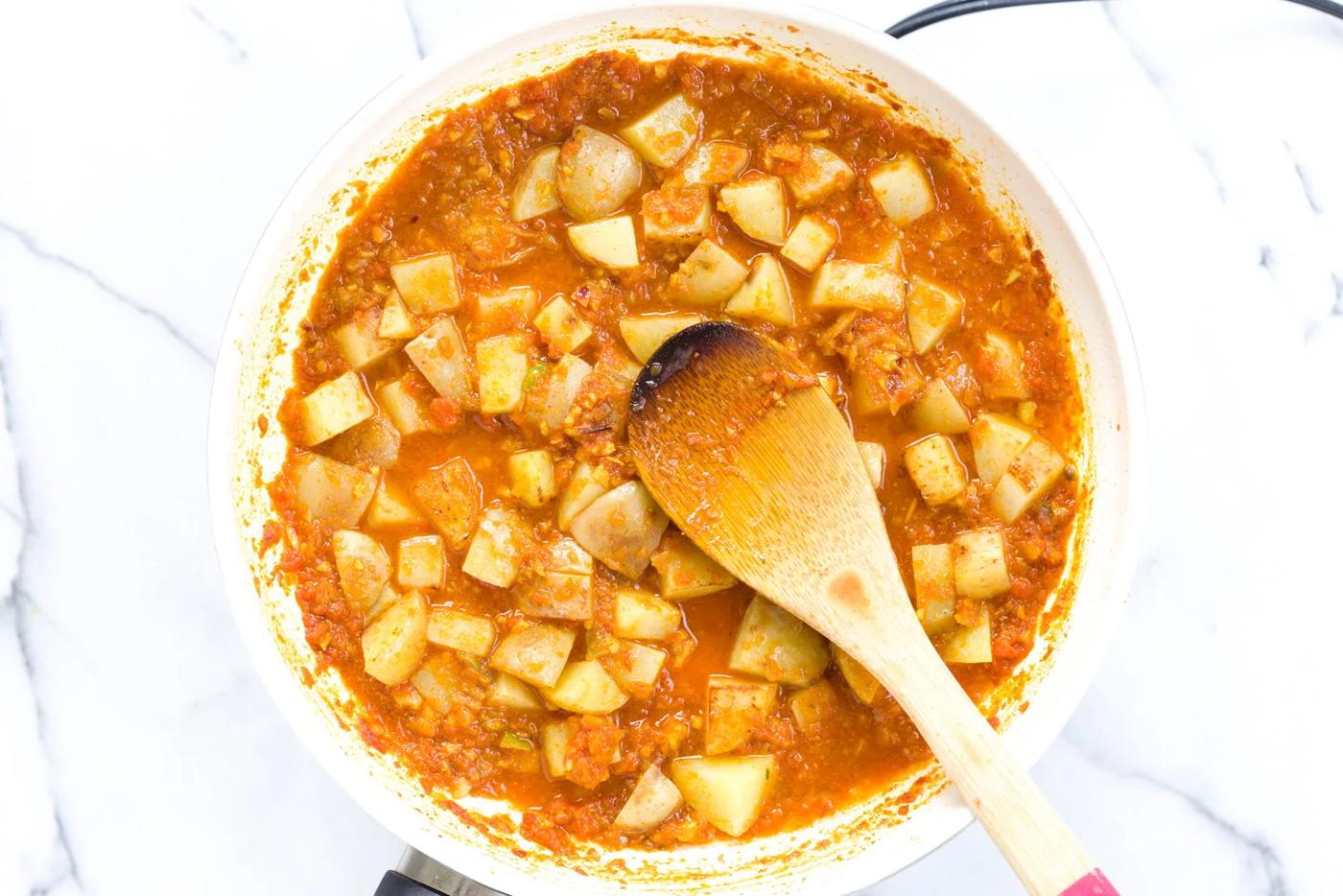 potato cubes simmering in a rich Indian tomato gravy