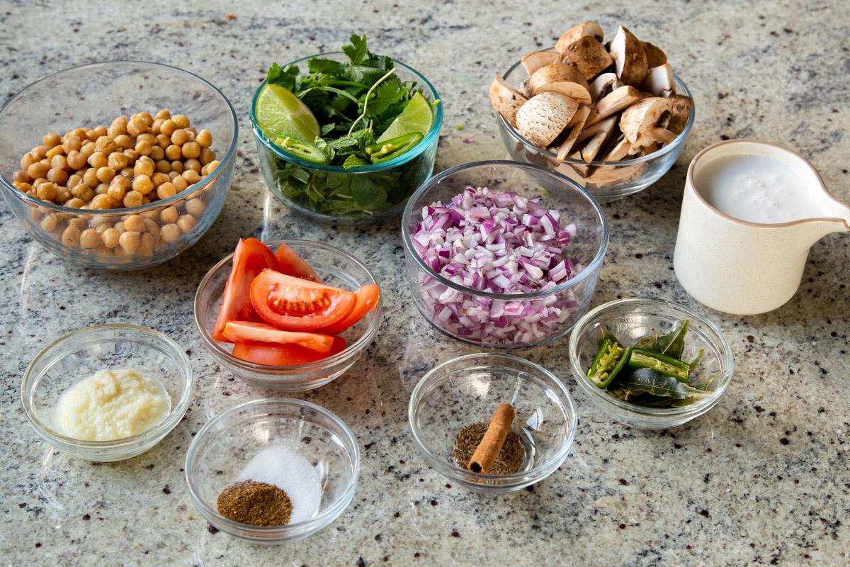 veggies, chickpeas, and spices in bowls on the kitchen counter