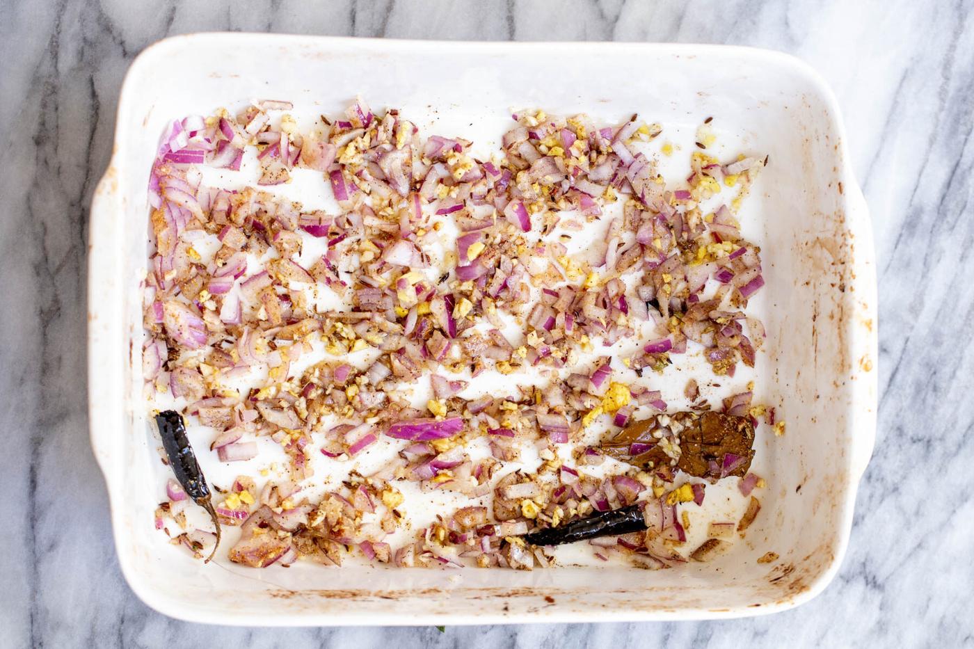 baked diced ginger and onions and spices in a white casserole dish