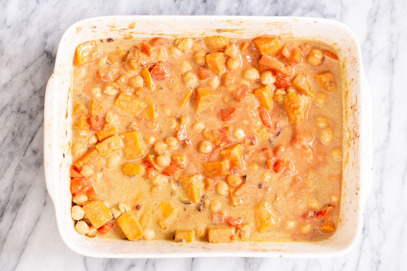 a casserole dish with chickpea sweet potato curry in creamy gravy