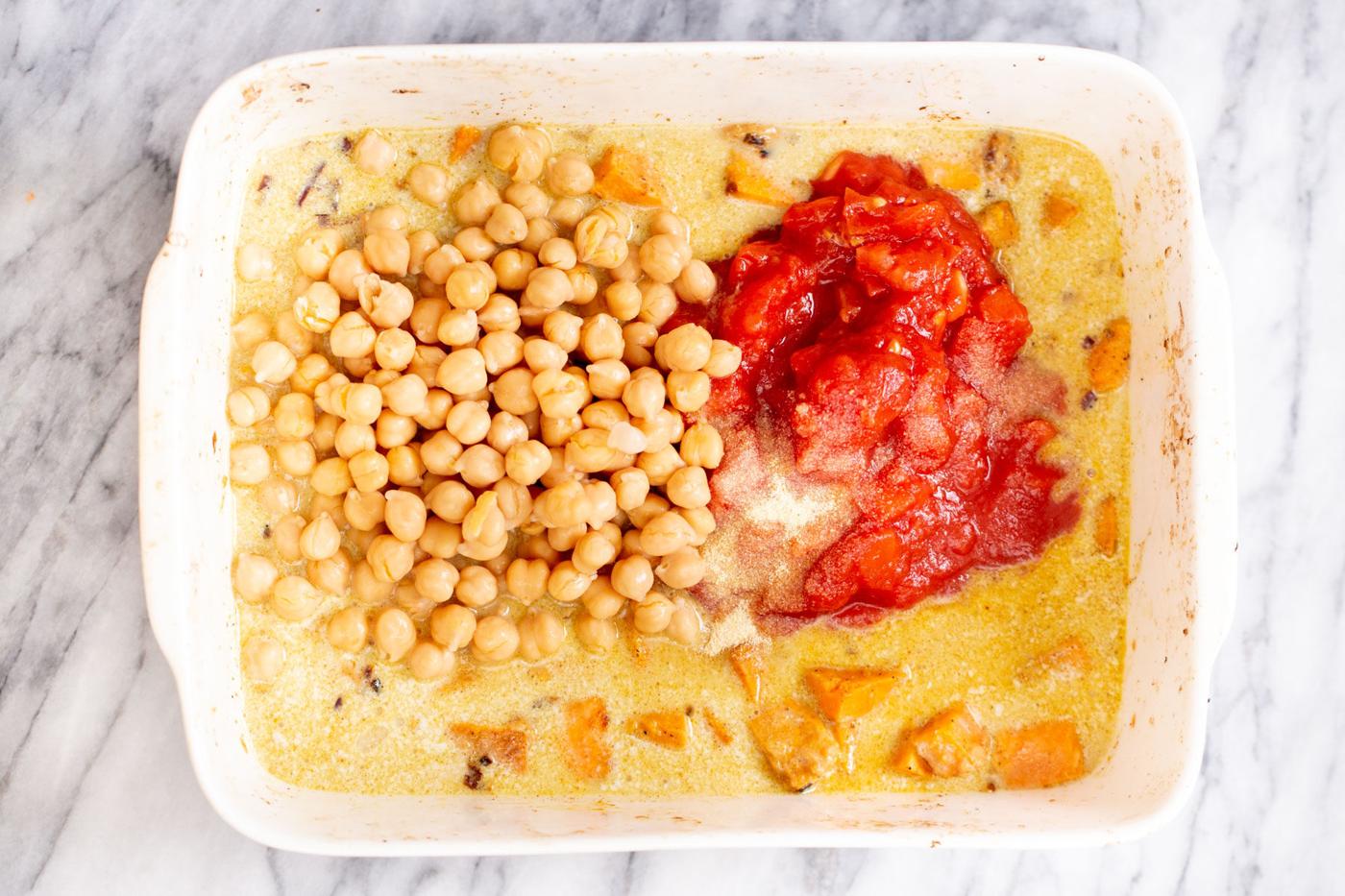 tomatoes and canned chickpeas being added to baked sweet potato curry