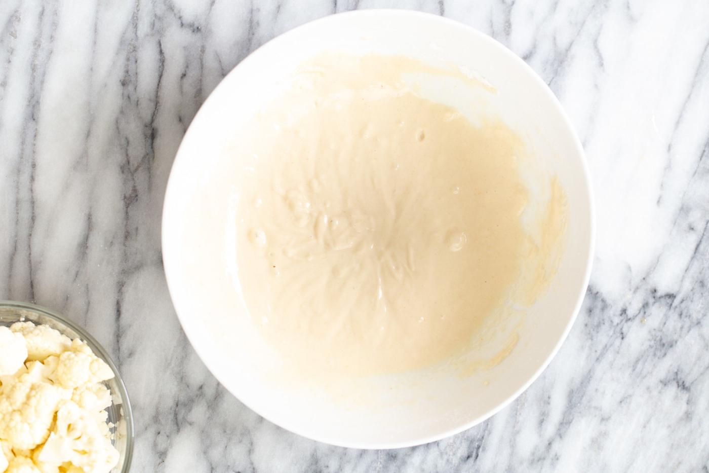batter for cauliflower manchurian in a small white bowl