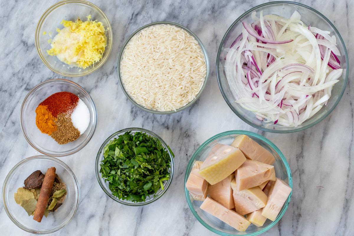 basmati rice, jackfruit, and other vegan biryani ingredients in bowls on the kitchen counter
