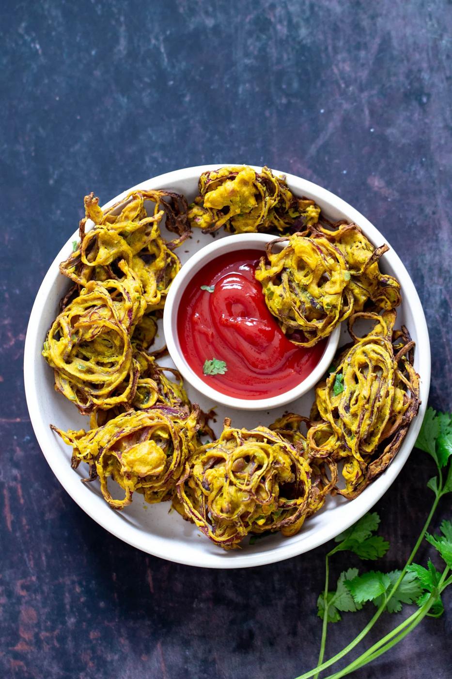 overhead shot of baked onion pakora served with ketchup as a dipping sauce