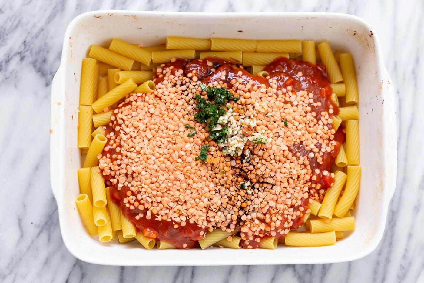 overhead shot of casserole dish with raw pasta, marinara and red lentils
