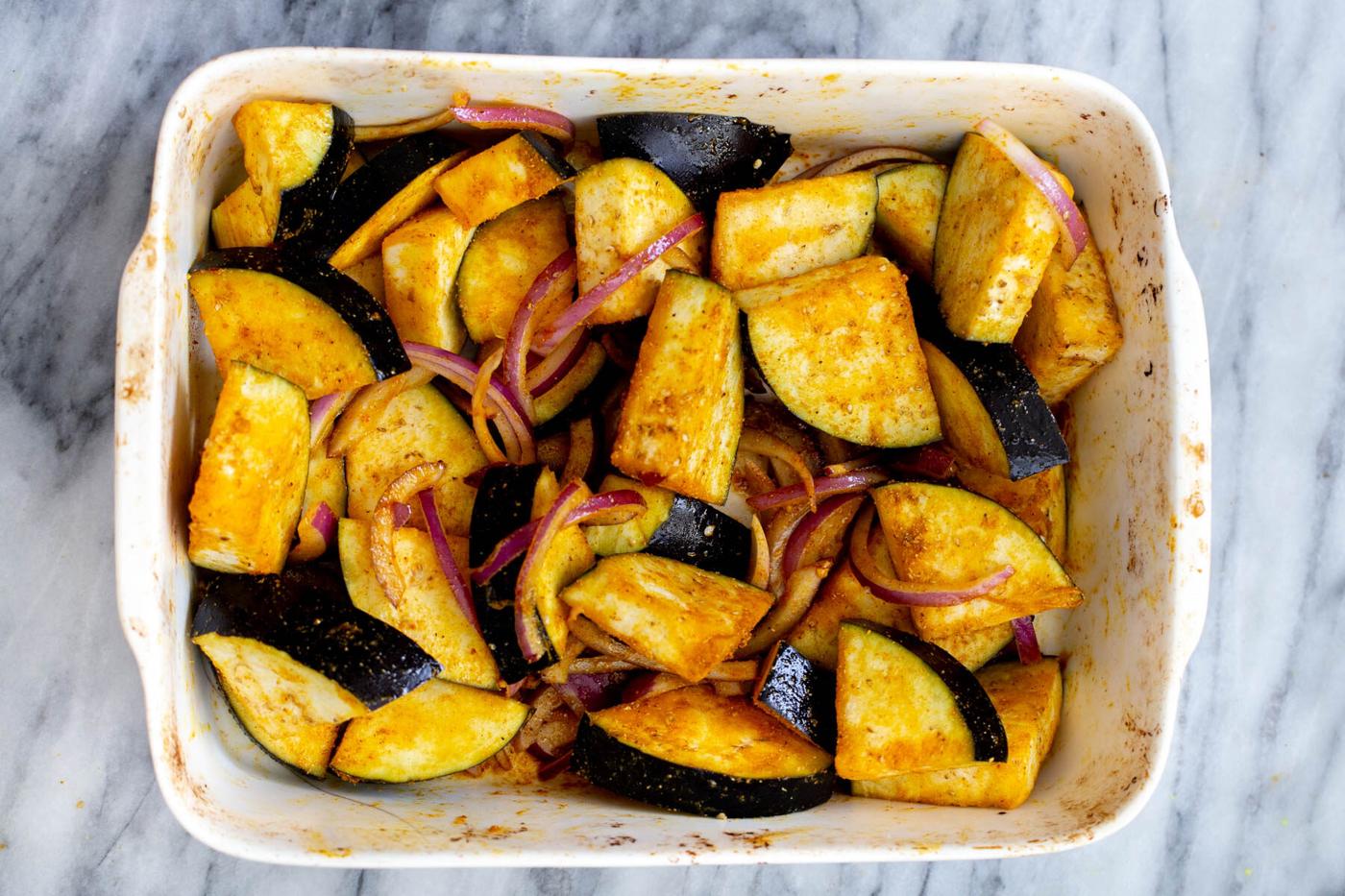 spiced eggplant spices and onions in a white casserole dish