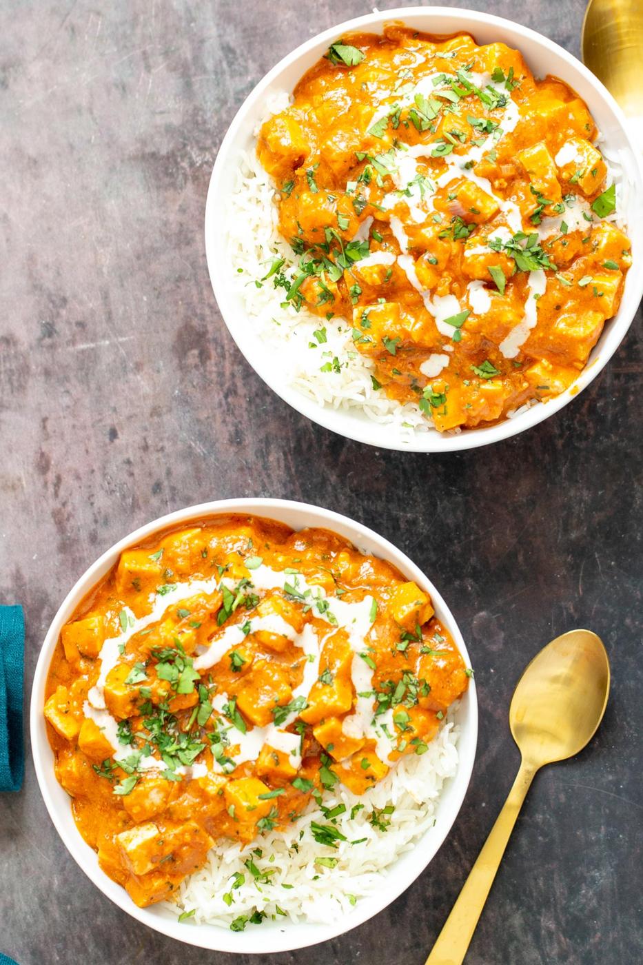 two bowls with vegan tofu curry casserole served with rice with a spoon on the side