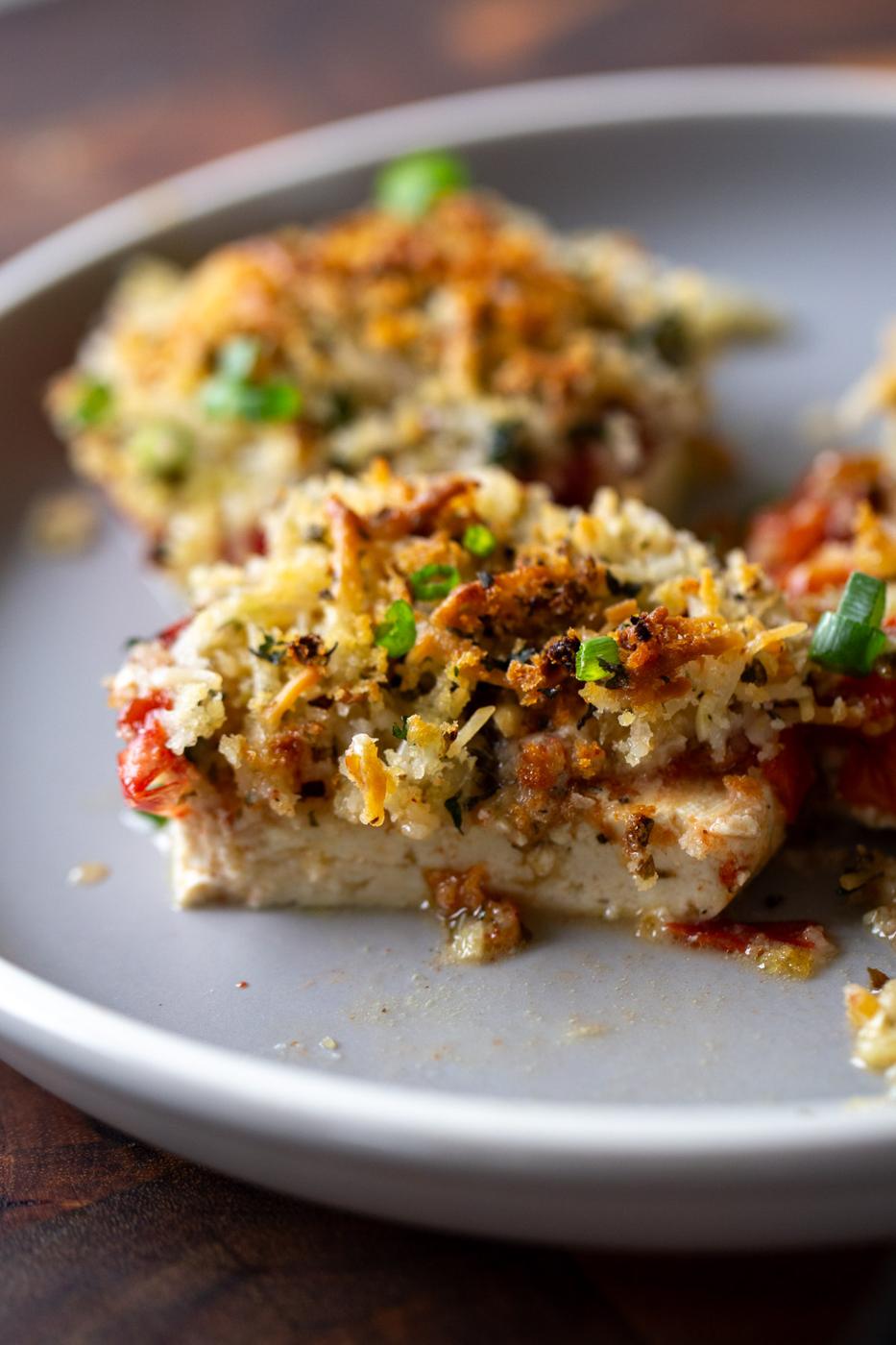 baked vegan caprese stacks on a plate with a bite taken out