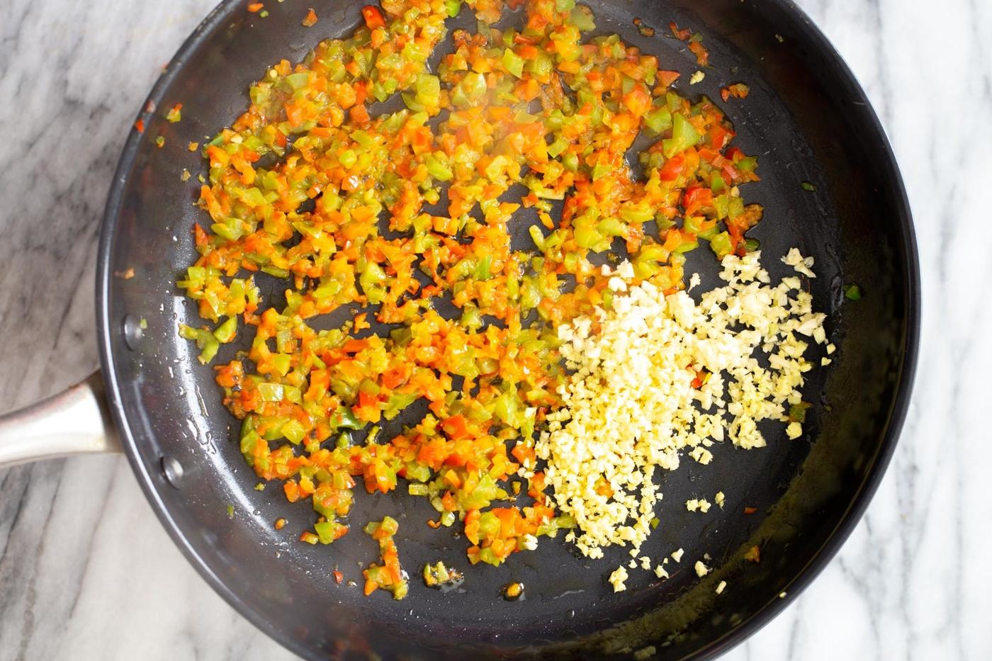 minced garlic being added to frying pan