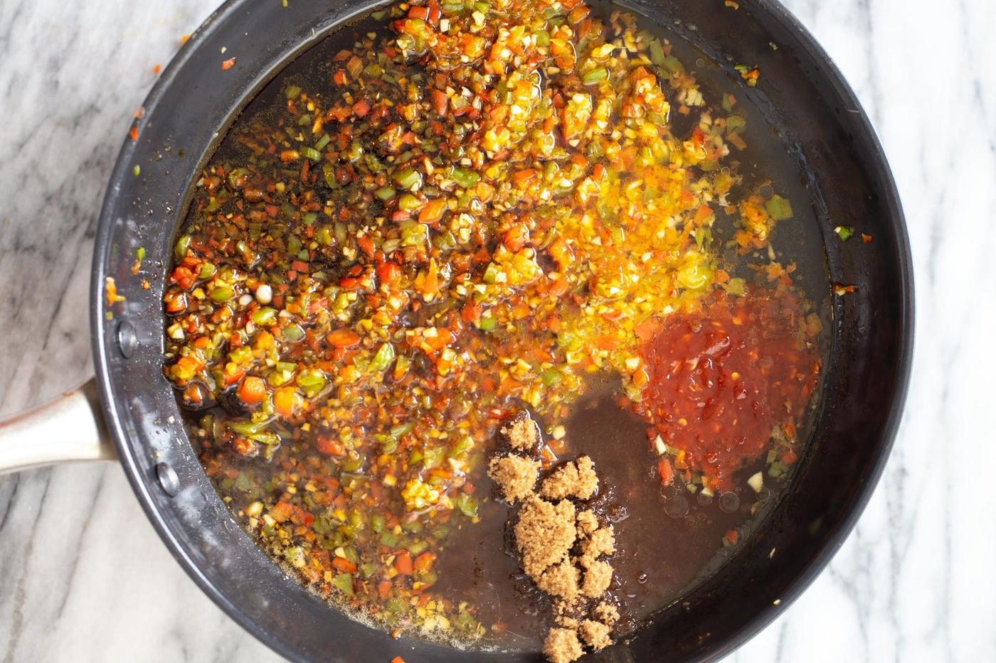 chili sauce and soy sauce being added to general tso sauce in skillet