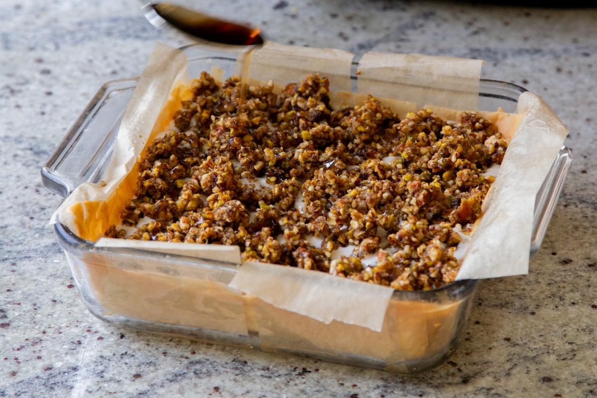 drizzling maple syrup over the baklava cheesecake, before freezing