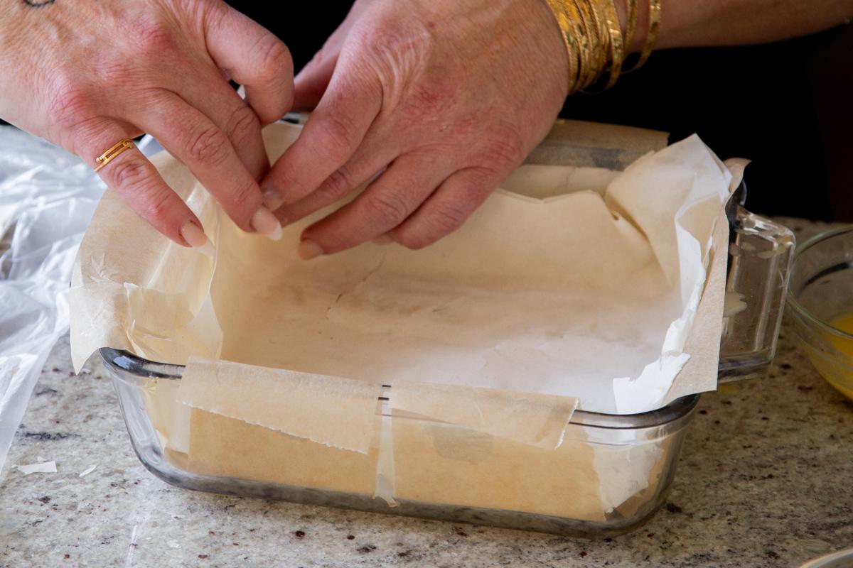 adding the buttered phyllo sheets to the baking pan