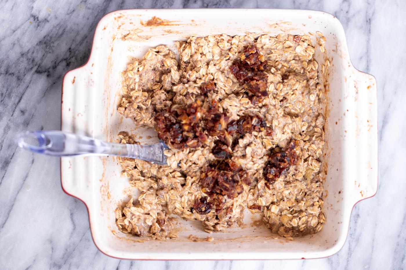 chopped dates being added to casserole dish banana oatmeal batter