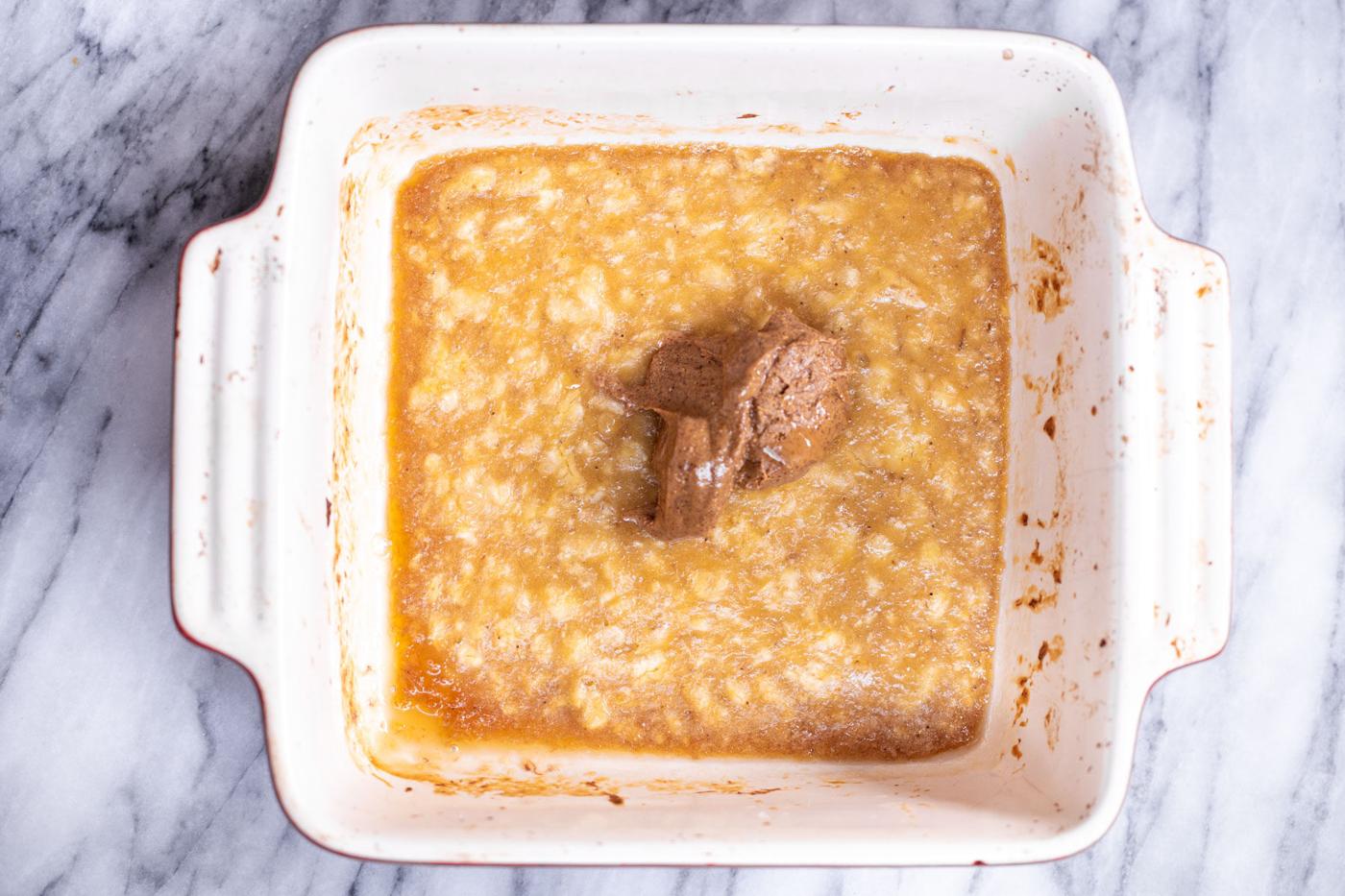 almond butter butter being added to banana puree in a casserole dish