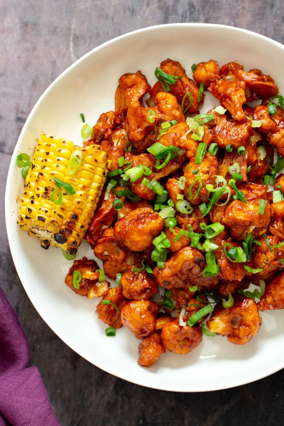 beer battered bbq cauliflower wings served with a piece of grilled corn on the cob