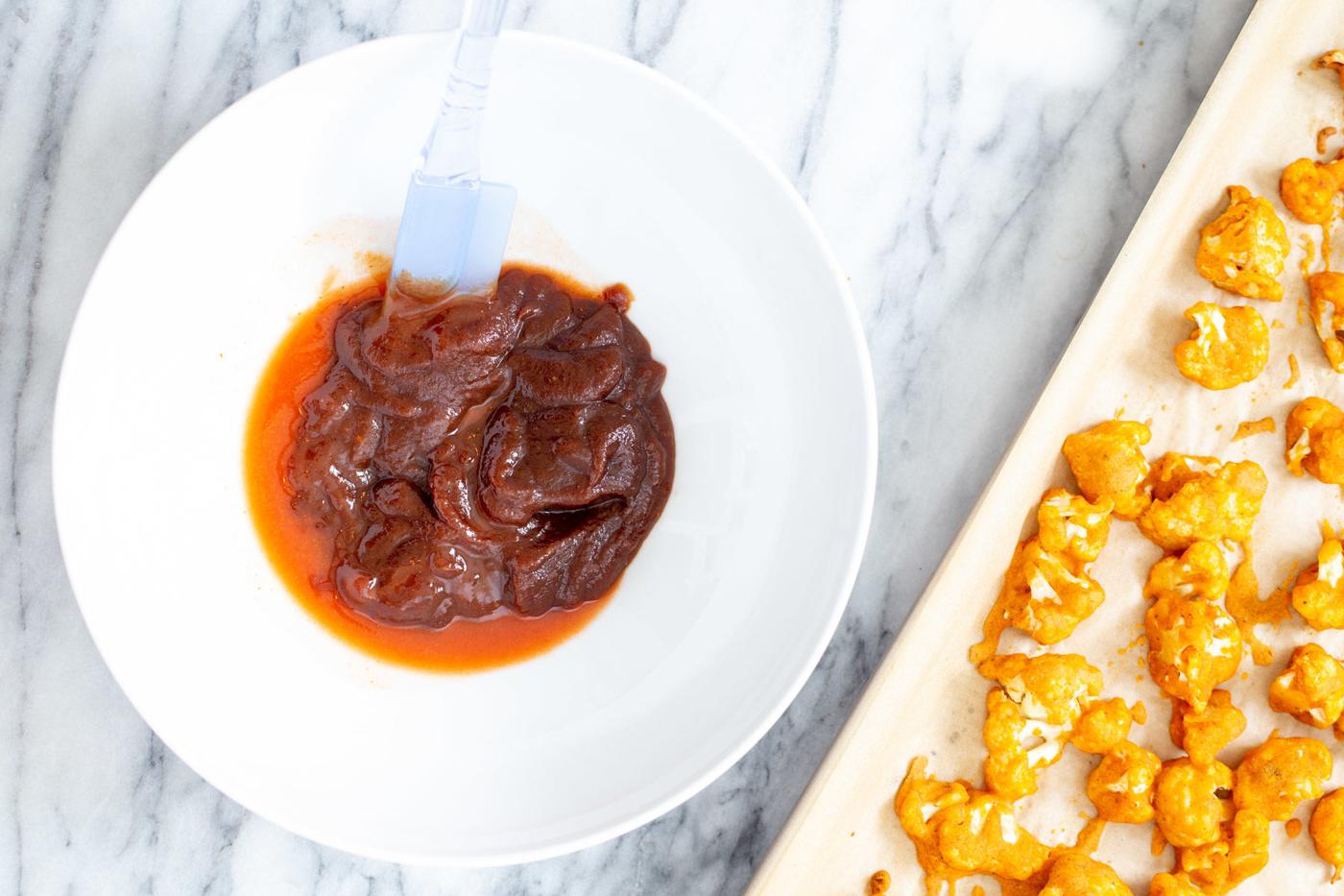 hot sauce and bbq sauce being mixed in a small dish
