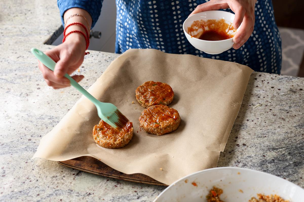 brushing BBQ sauce onto the patties