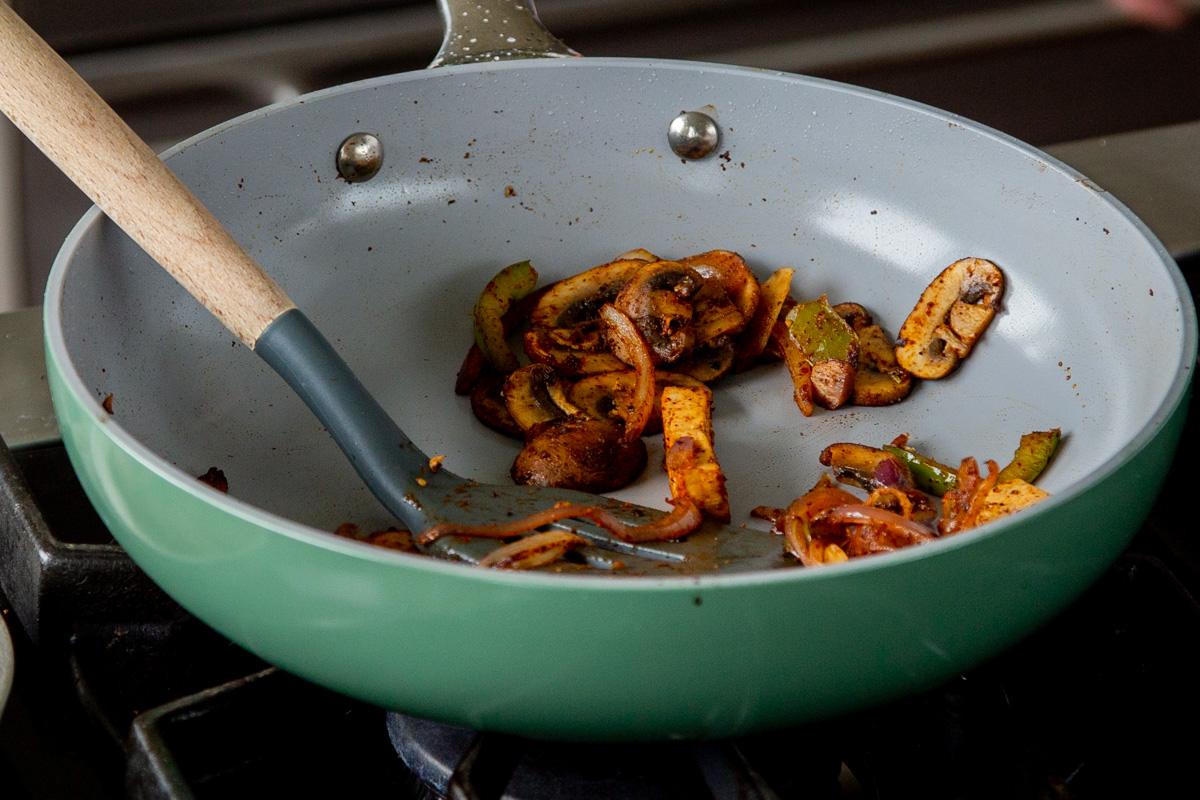 cooked tofu, peppers, and onions in the pan after setting half aside for garnish