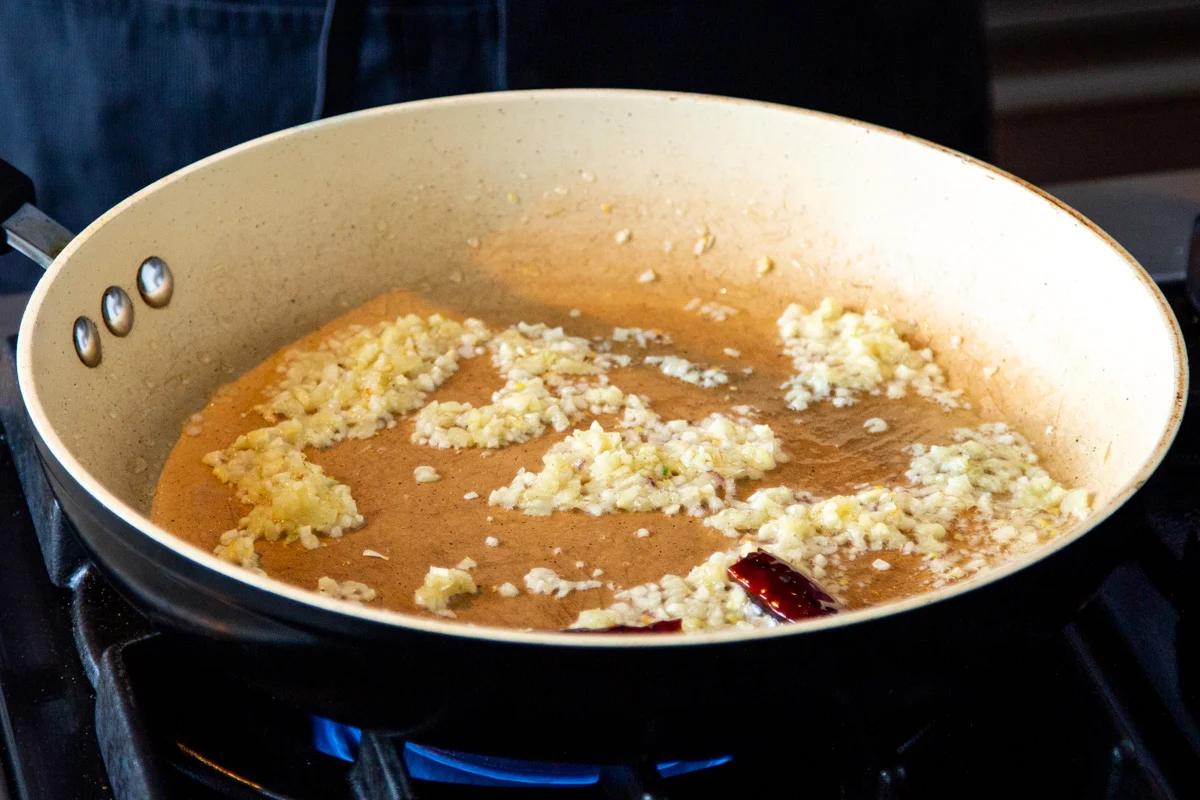 minced garlic, dried chili and ginger sauteeing in a frying pan