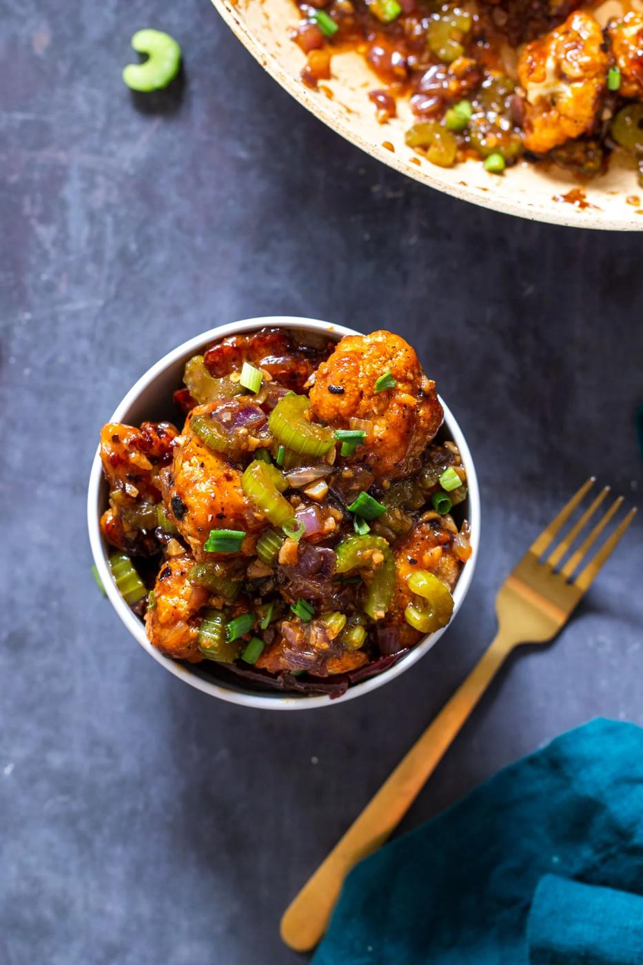 a small bowl of vegan black pepper cauliflower with a golden fork on the side