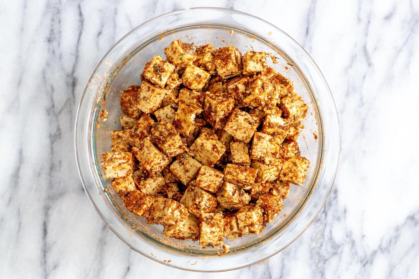 tofu cubes tossed with spices in a glass bowl