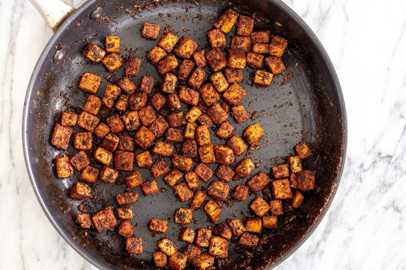 tofu cubes covered in spices in a black skillet