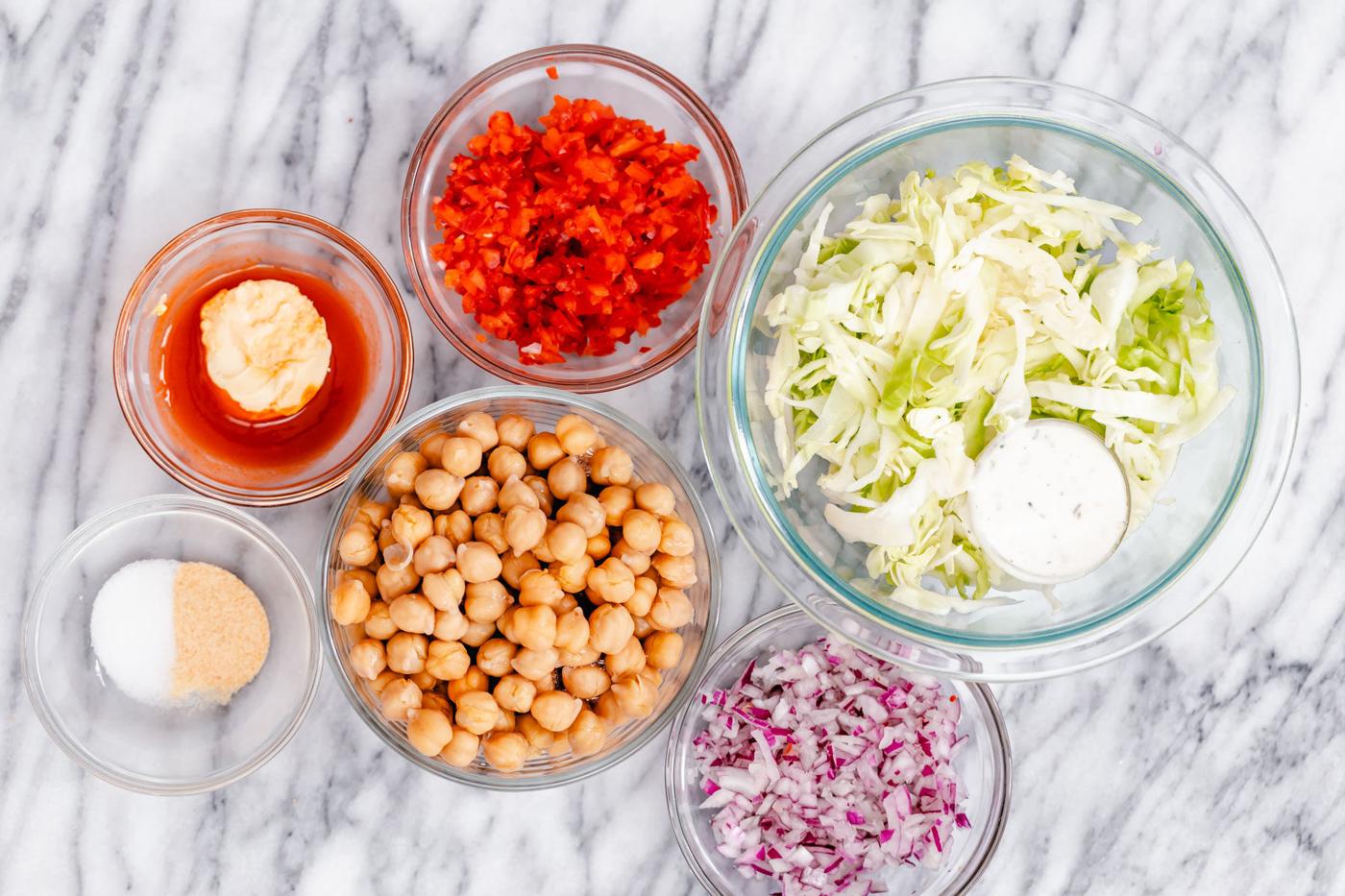 ingredients for buffalo chickpea salad sandwich assembled on a marble countertop