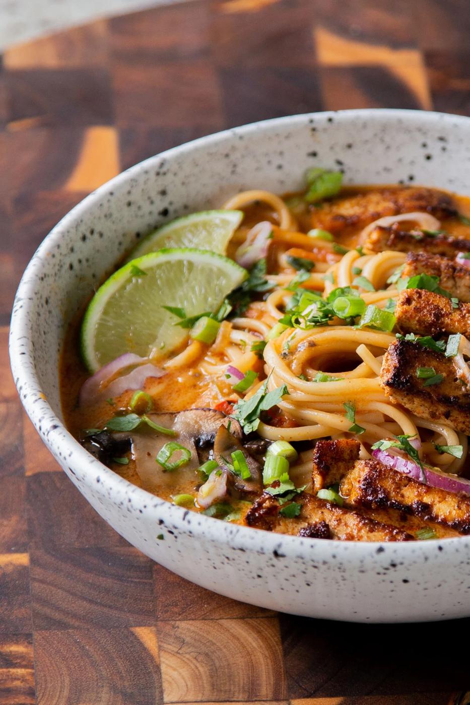 close-up of a bowl of butter ramen with tofu and a lime wedge