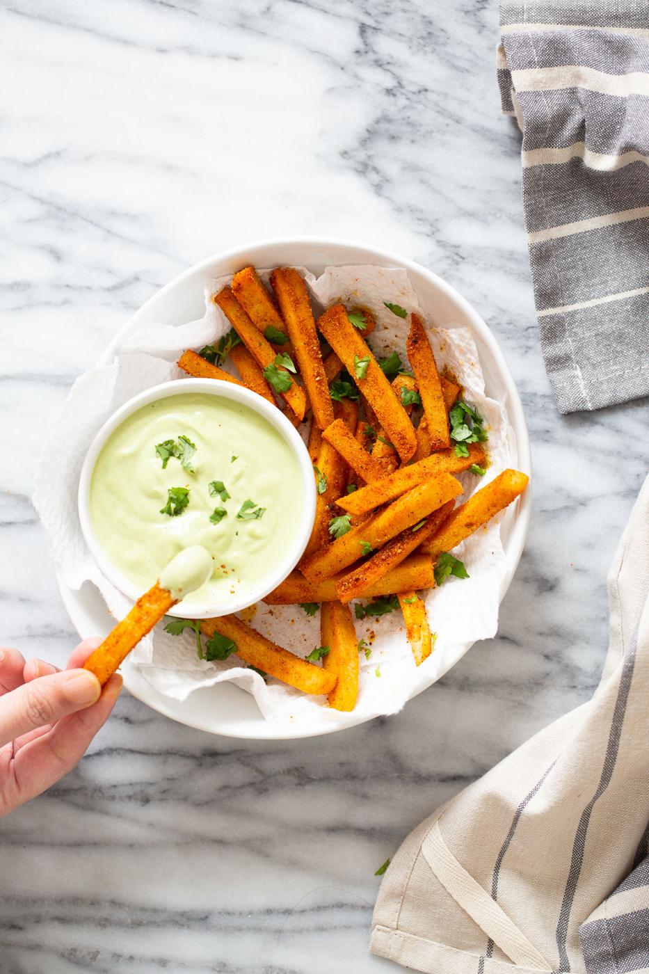 a vegan chickpea flour frie being dipped into cilantro lime dip