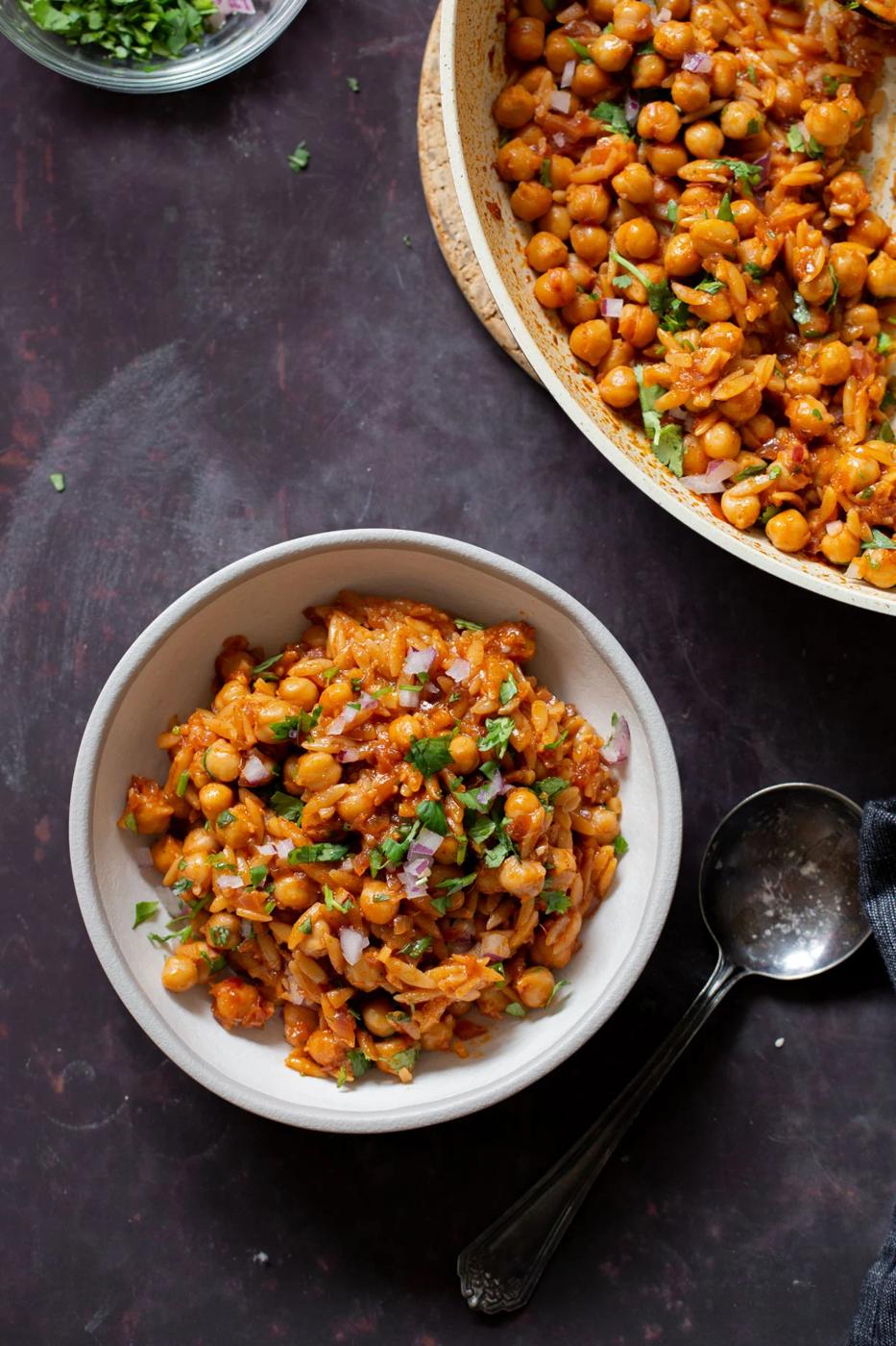 bowl of vegan cajun orzo next to the pan