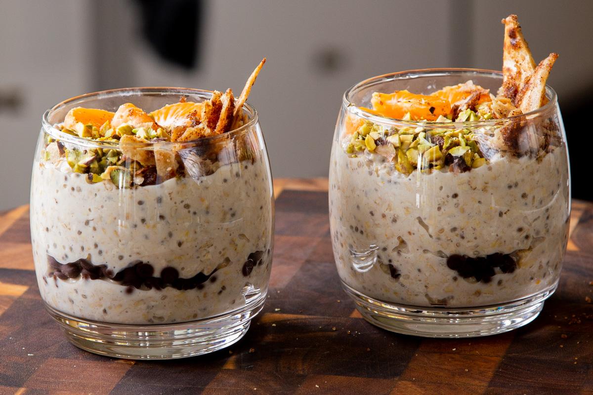 glasses full of cannoli overnight oats topped with oranges, pistachios, and crispy cinnamon sugar tortilla pieces, so you can see the chocolate chips layer