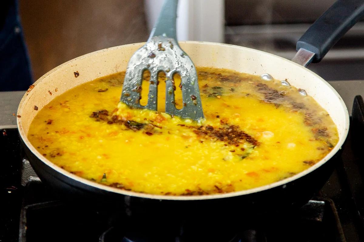 tempering being added to dal in a saucepan