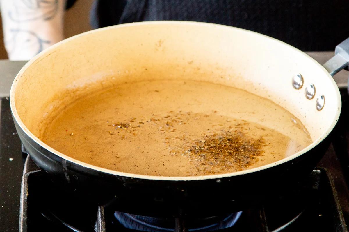 a sauteeing pan with oil with some cumin and crushed pepperflakes