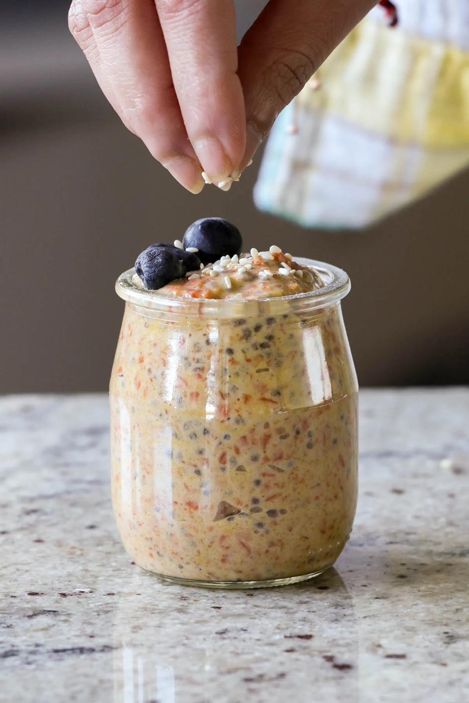sprinkling pecans on top of carrot cake overnight oats