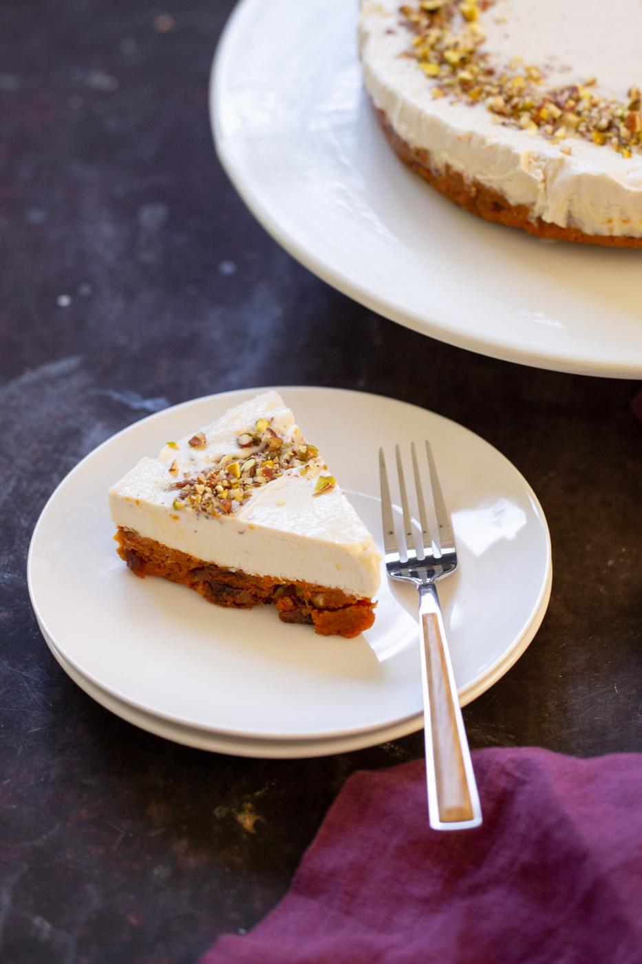 slice of carrot cake cheesecake on a plate next to the full cake