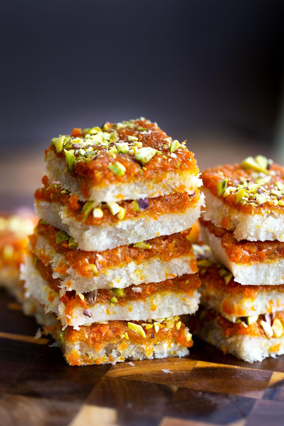 stacked carrot halwa coconut burfi bars on a wooden board