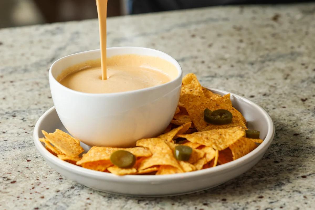 pouring cashew nacho cheese into a serving bowl