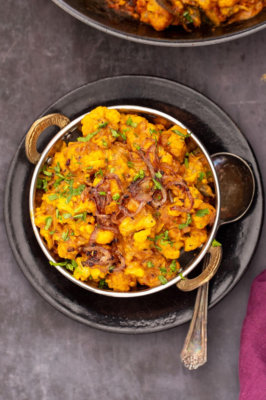 glutenfree Indian gobi do pyaza served in an Indian dish with a spoon on the side