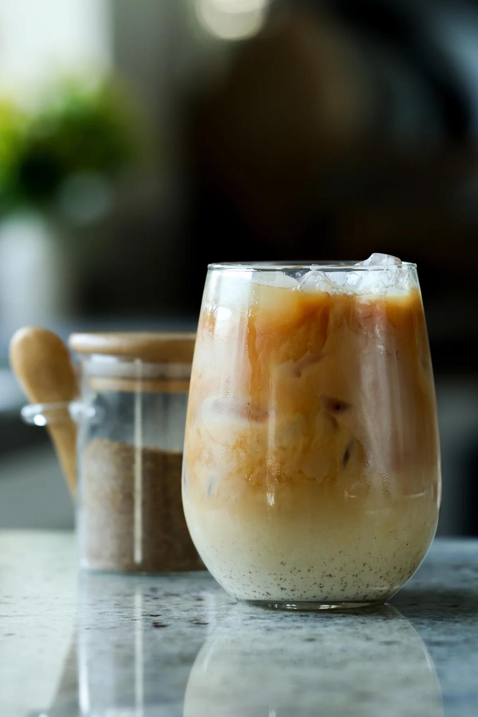 glass of iced chai with a jar of chai masala in the background