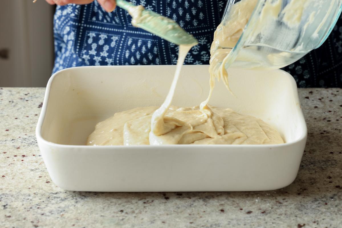 pouring cake batter into the greased pan
