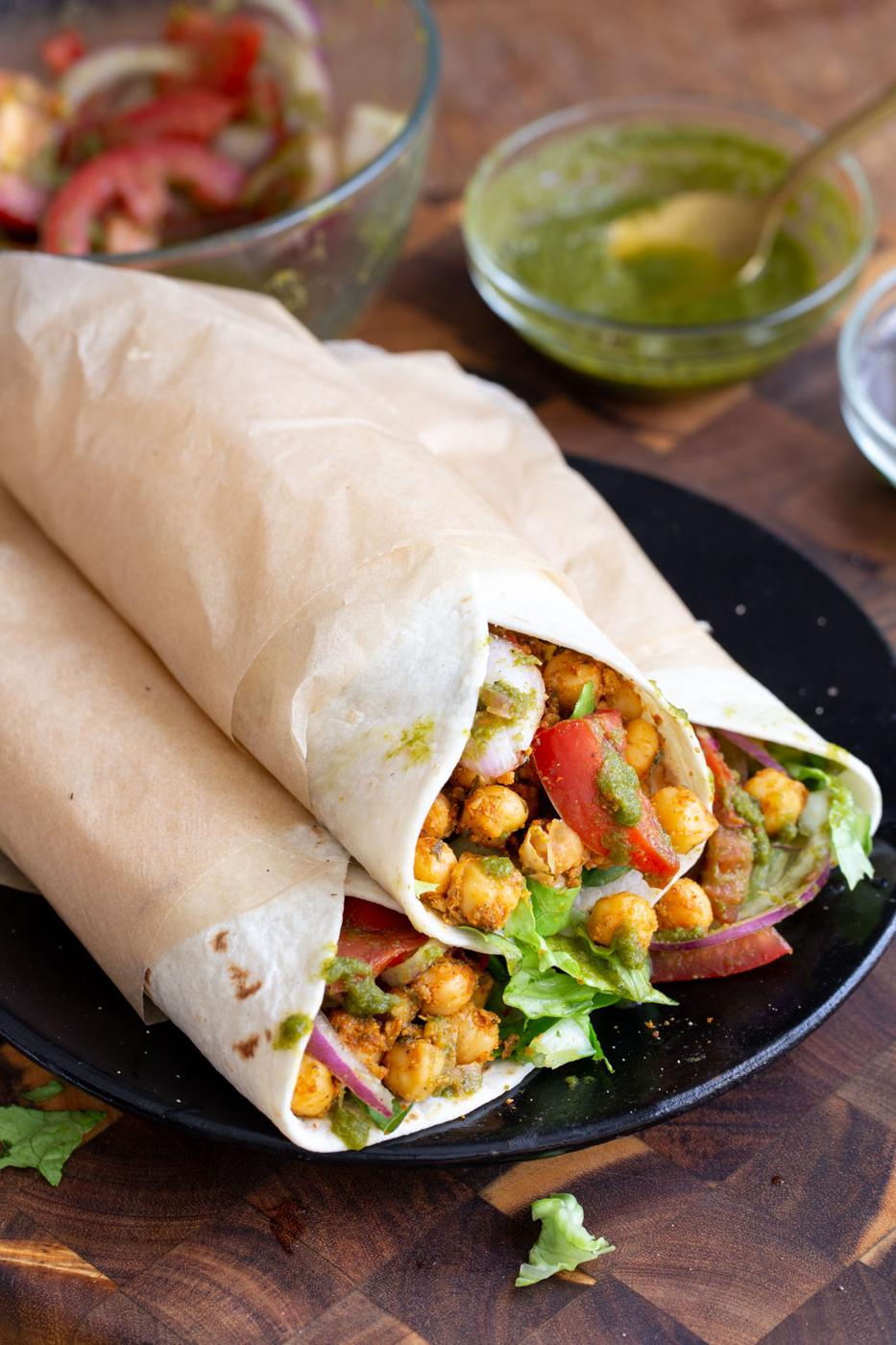 three chickpea kathi rolls on a black plate