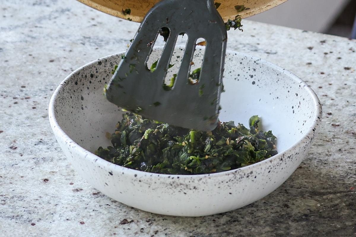 adding spinach mixture to a bowl